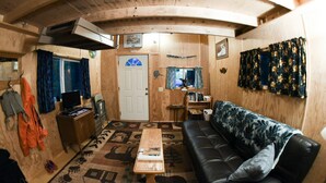 Un espacio habitable compacto con sofá, una mesa de centro, televisor y una puerta con ventana.