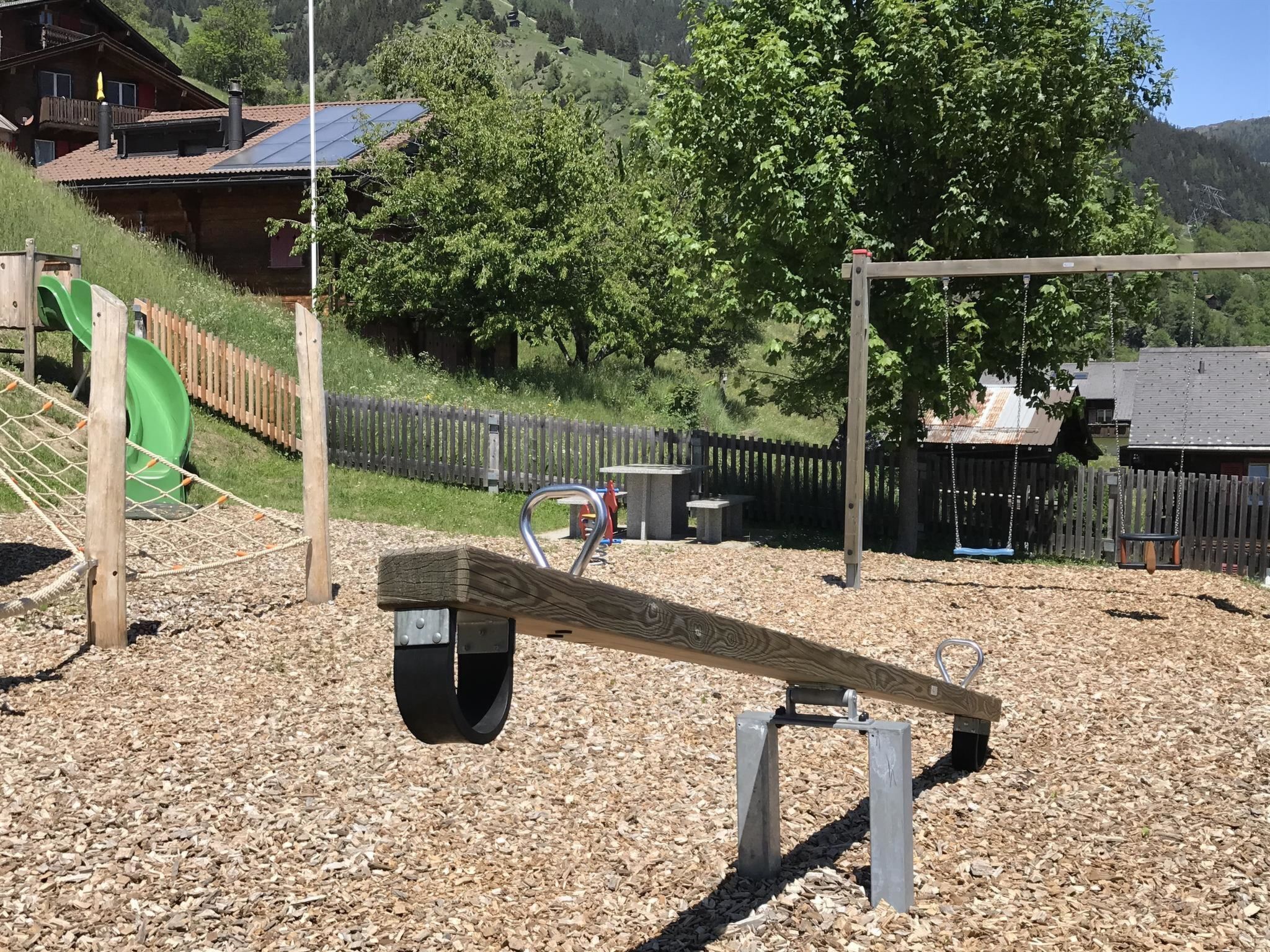 A playground with a seesaw, a slide, and a swing set.