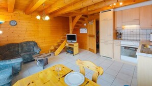L’intérieur d’un chalet en bois chaleureux et accueillant, comprenant un espace de vie, une table à manger et une cuisine.