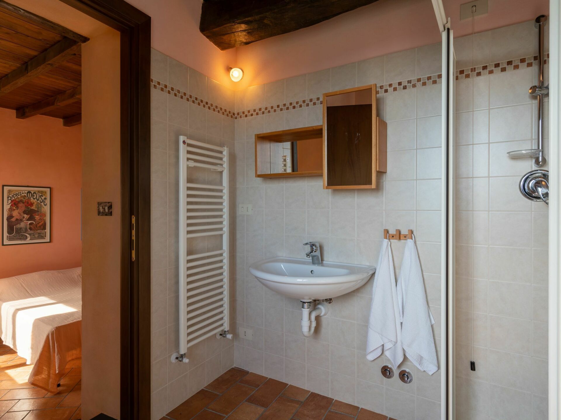 A bathroom with a white sink, a mirror, a towel rack, and a shower.