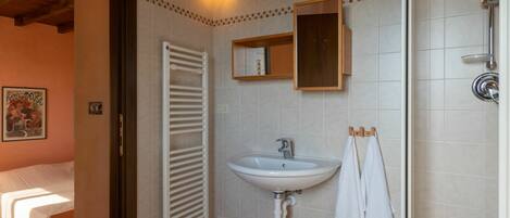 A bathroom with a white sink, a mirror, a towel rack, and a shower.