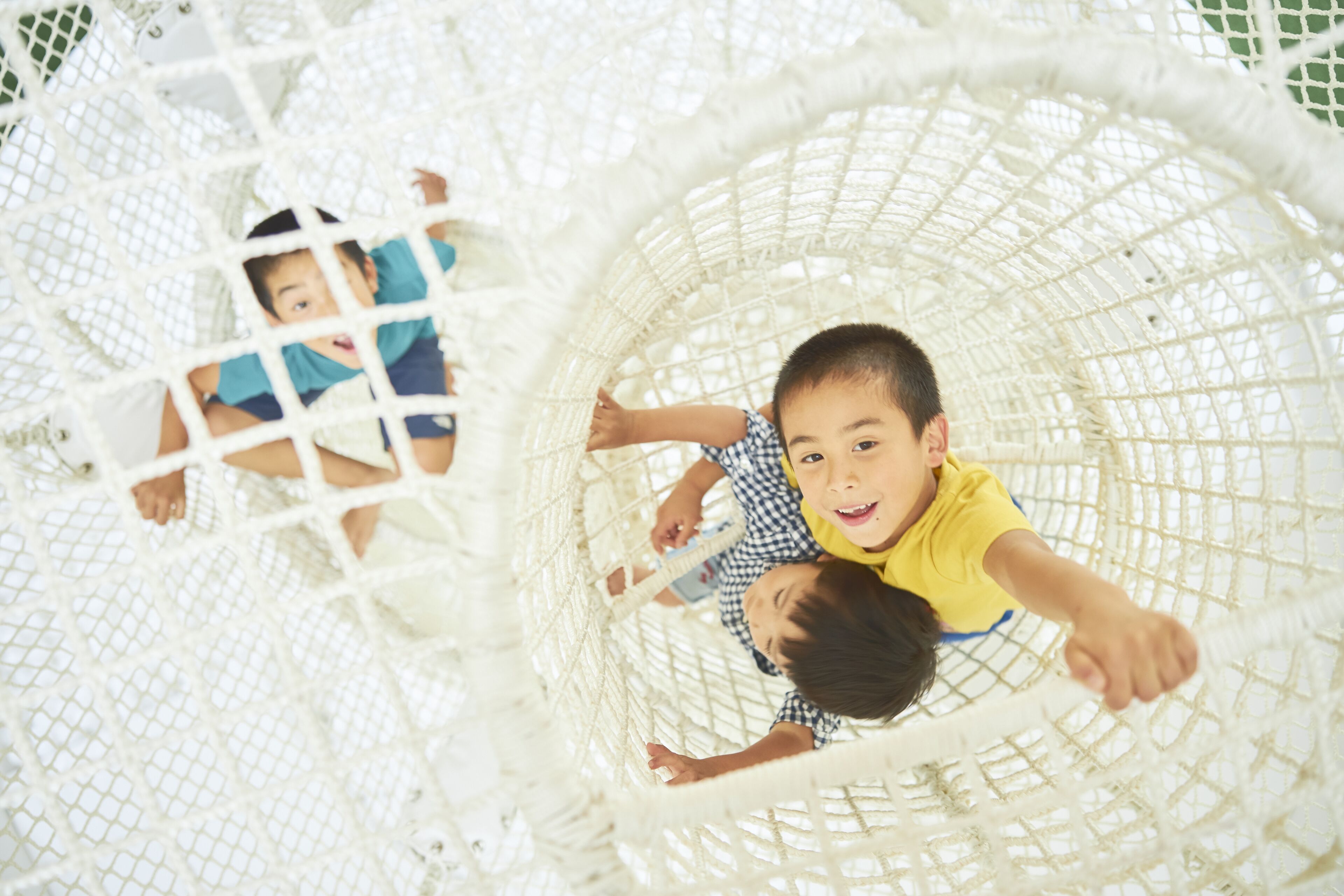 A white netted play structure with children inside.