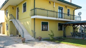 A two-story building with a balcony, a staircase, and outdoor seating. - Nice apartment for 6 guests with WIFI, TV, patio and pets allowed (Eraclea)