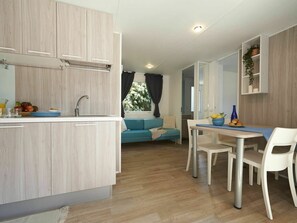 Eine moderne Küche mit Holzausstattung, einem Spülbecken und einem Essbereich mit Tisch und Stühlen.