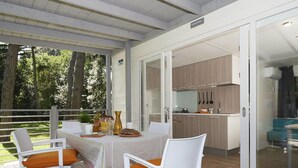 A covered outdoor dining area with a table and chairs, a view of a modern kitchen, and a glass door leading to a balcony. - Nice apartment in villa for 5 guests with WIFI, pool, A/C, TV and terrace (Cellole)