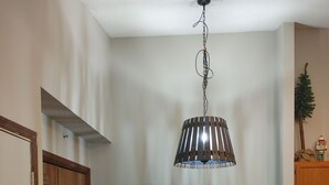 Un coin repas avec une table et des chaises en bois, un luminaire suspendu et un appareil électroménager blanc dans un coin.
