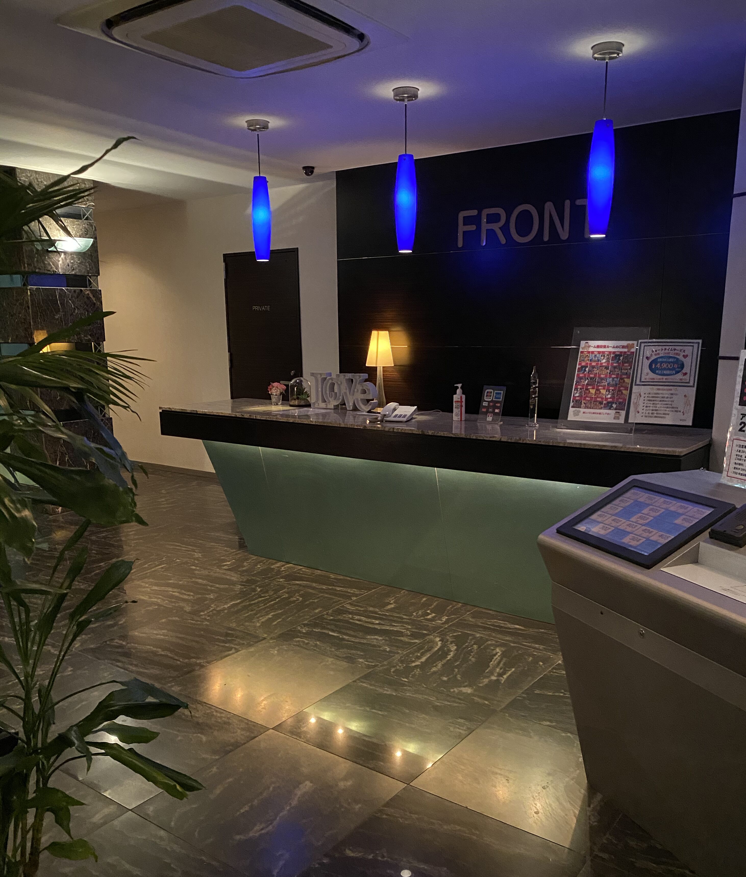 A reception desk with a 'FRONT' sign, a lamp, a phone, and a digital display.