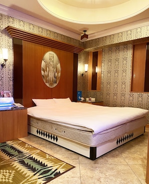 A large bed with a headboard, a bedside table, a mirror, and a patterned wall. - Hotel Venus Ritz - Adults Only (Seto)