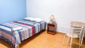 Un dormitorio pequeño y ordenado con una cama individual, una mesita de noche con lámpara y una silla.