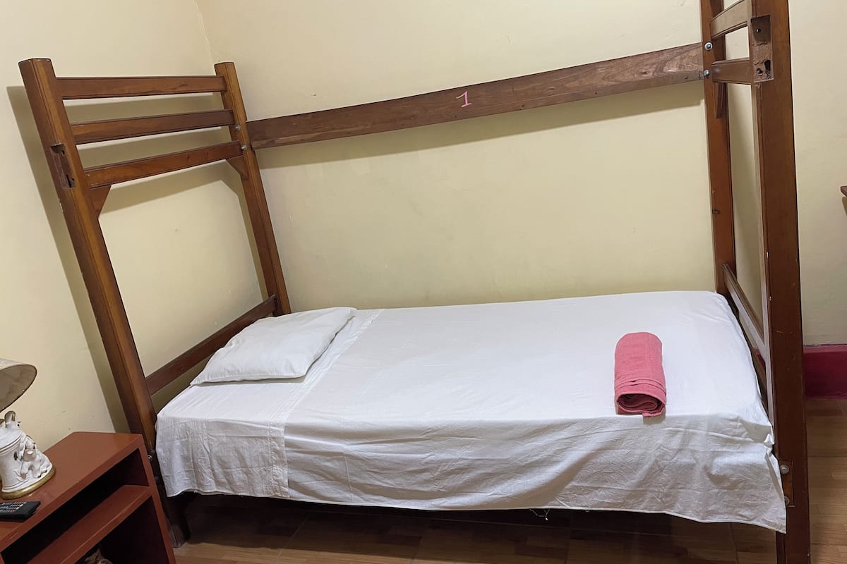 Una cama litera con un colchón blanco y una toalla rosa.