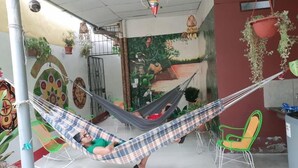 Una hamaca en una habitación con un mural, una silla y plantas en macetas.