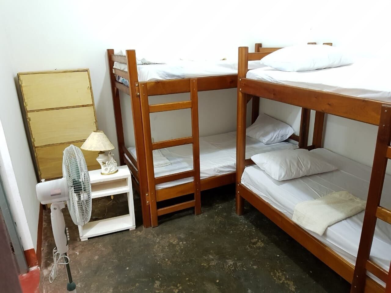 Habitación con literas, una mesita pequeña y un ventilador.