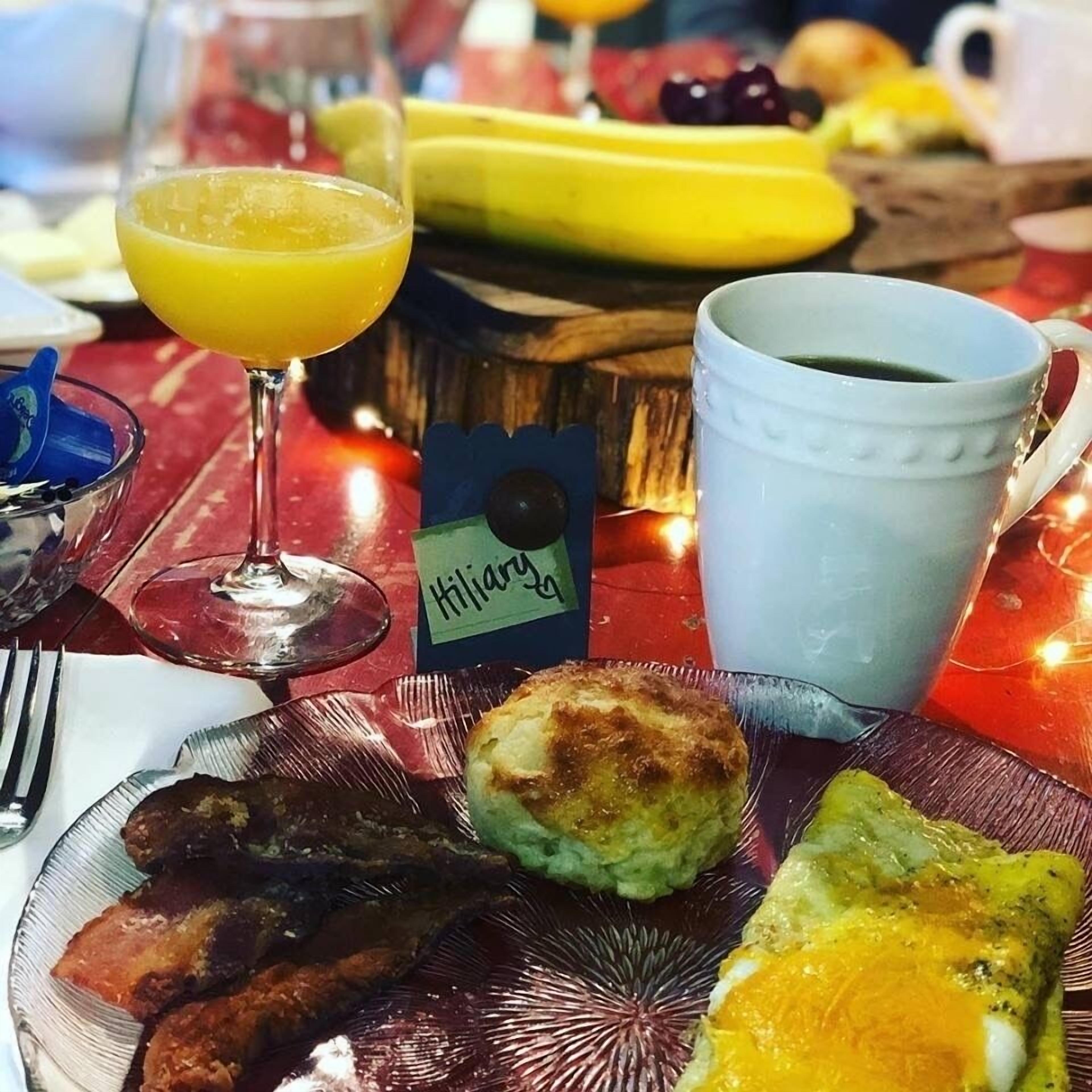 Aamiaispöytä, jossa on lautanen täynnä ruokaa, lasi appelsiinimehua ja kahvikuppi.