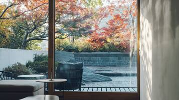 Un intérieur moderne avec une grande fenêtre donnant sur un jardin aux couleurs automnales.