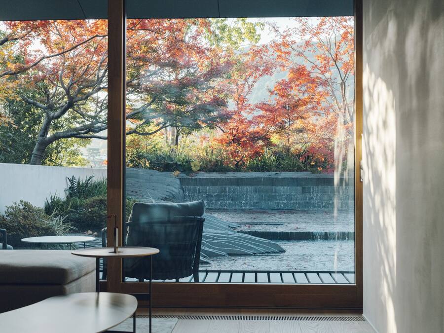 Un intérieur moderne avec une grande fenêtre donnant sur un jardin aux couleurs automnales.