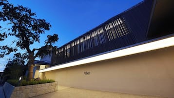 Un edificio moderno con techo plano, pared de color claro y estructura vertical oscura.