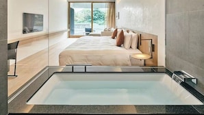 A modern hotel room with a large bed, a built-in bathtub, and a view of the outdoors. - MUNI KYOTO (Kyoto)