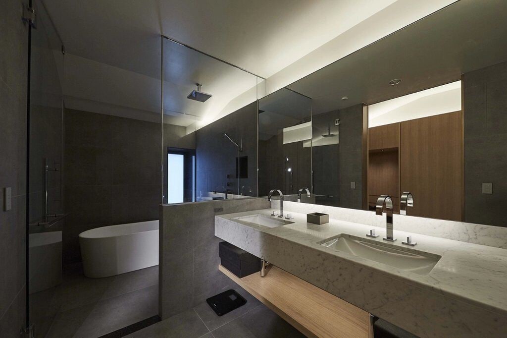 A modern bathroom with a large mirror, two sinks, a bathtub, and a shower.