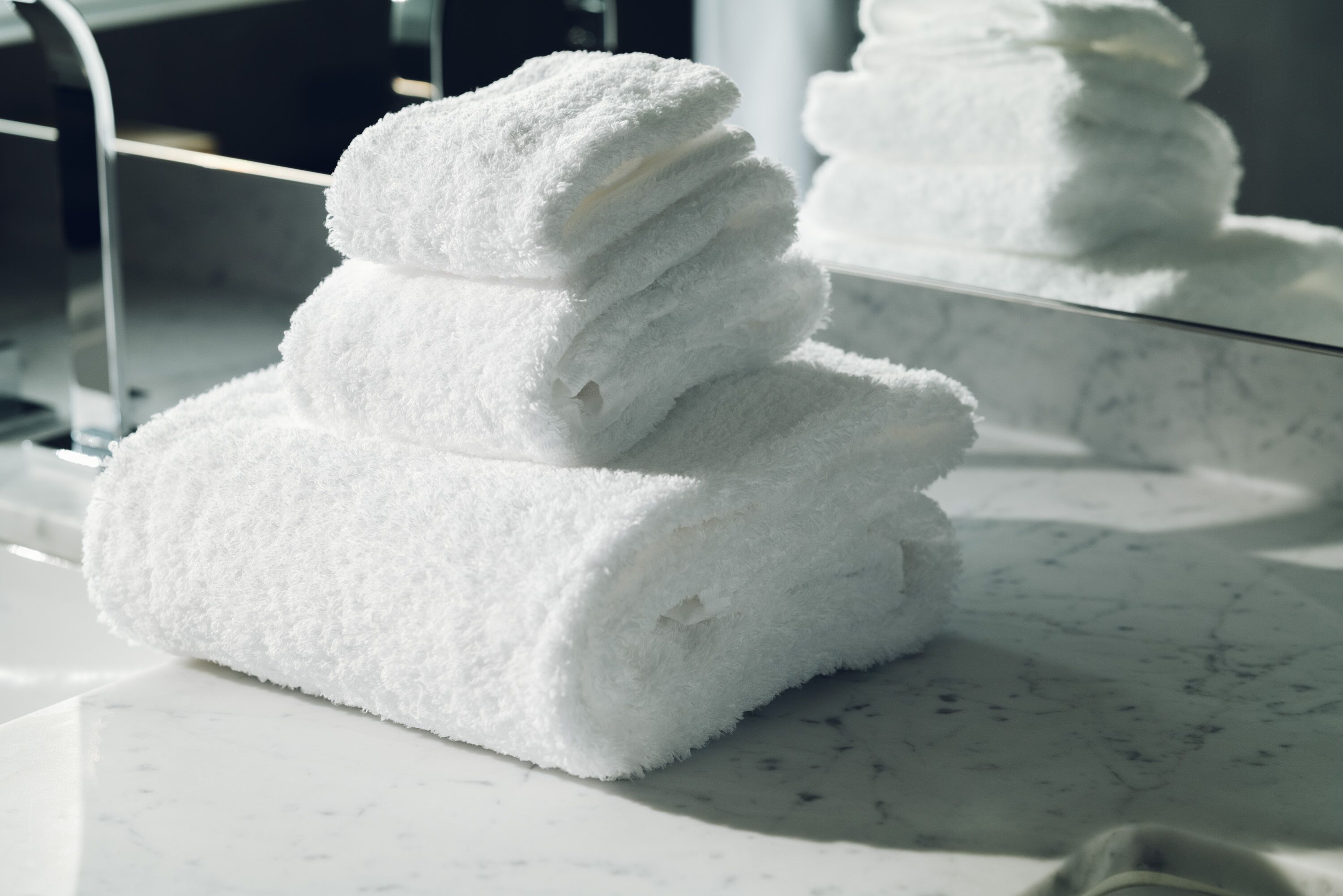A stack of white towels on a marble surface.