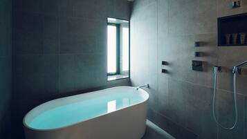 A modern bathroom with a freestanding bathtub, a window, and a built-in shower area.