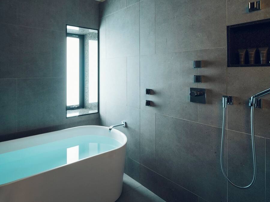 A modern bathroom with a freestanding bathtub, a window, and a built-in shower area.