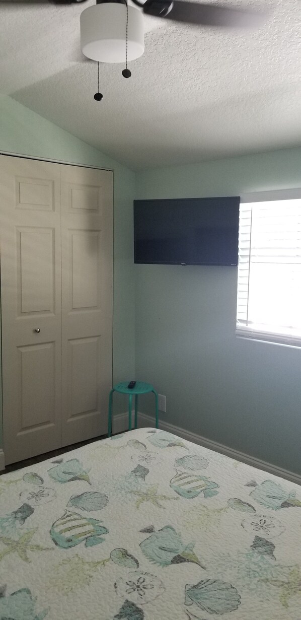 A bedroom with a bed, a closet, a window, and a ceiling fan.