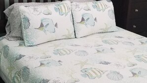 Una cama con una colcha de estampado floral, dos almohadas a juego, un cabecero de madera oscura y una obra de arte enmarcada sobre la cama.