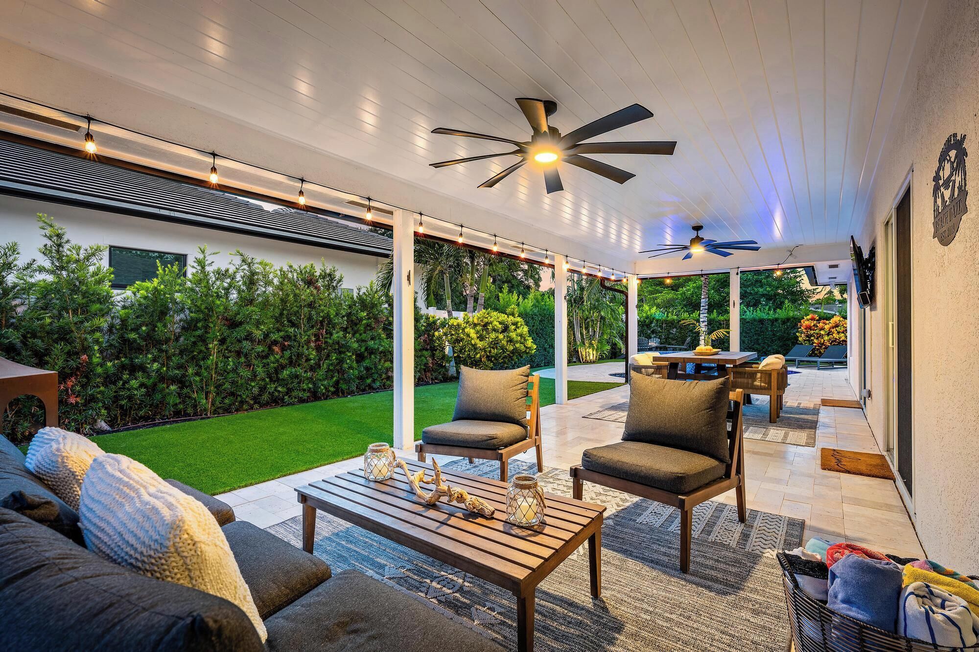 An outdoor patio area with a ceiling fan, string lights, and a dining table with chairs.