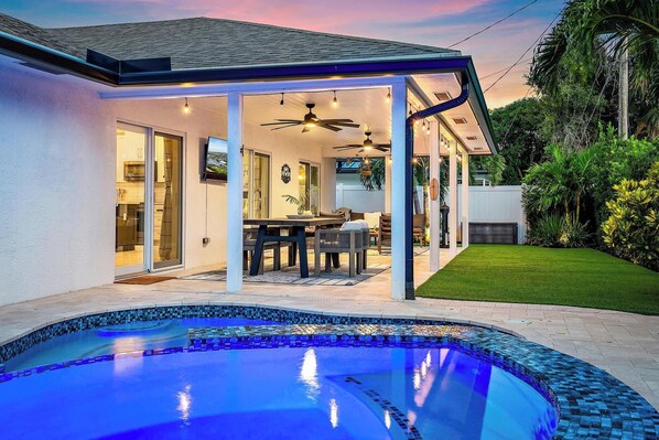 Una propiedad residencial con piscina, un patio cubierto y un césped bien cuidado.