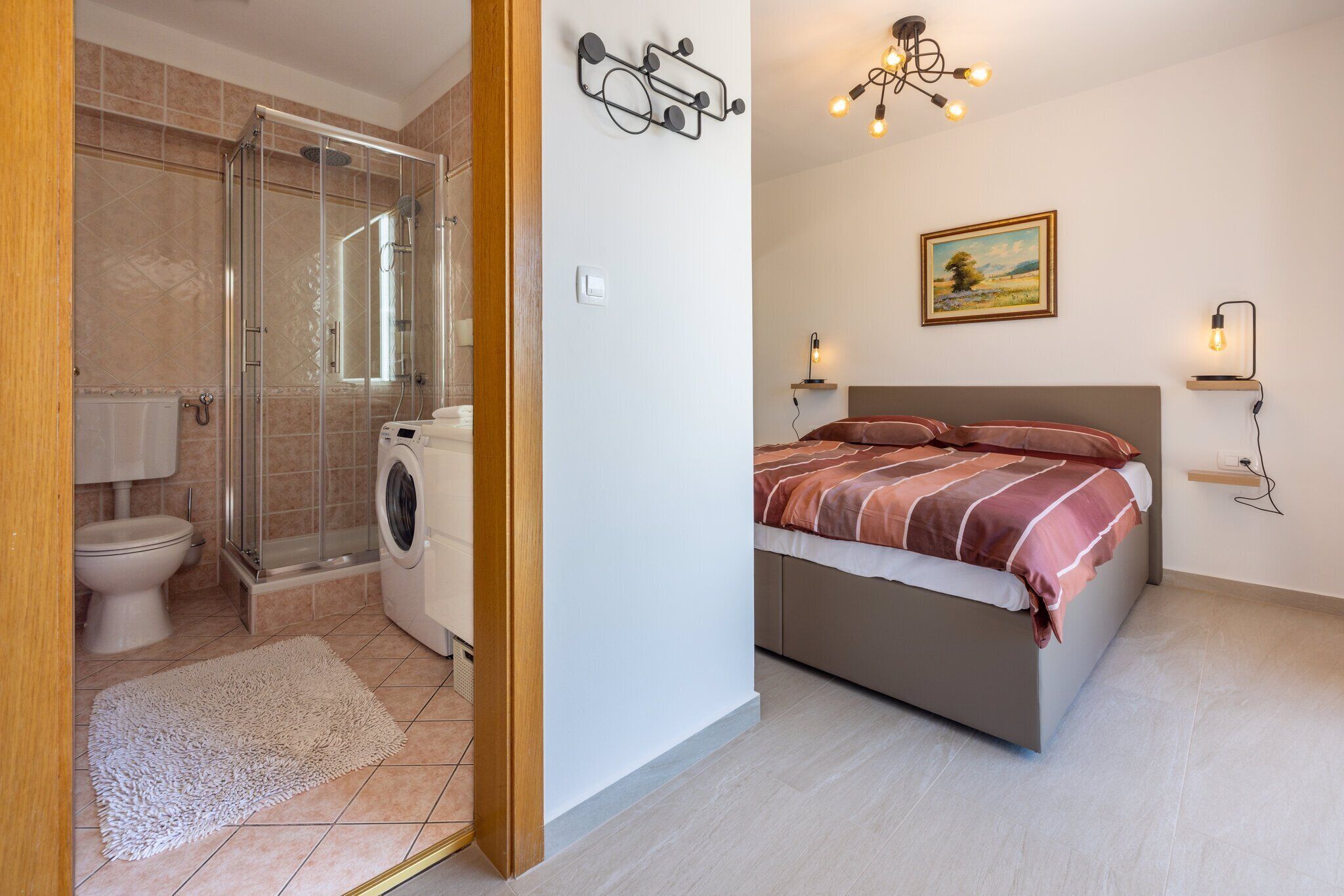 Un bagno moderno con cabina doccia in vetro, un water e una lavatrice.