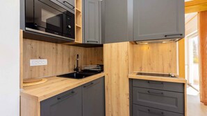 Une cuisine compacte avec des meubles en bois, un micro-ondes noir et un four encastré.