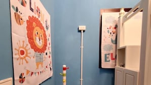 Un baño pequeño con una pared azul, un perchero blanco con ganchos de colores, un inodoro blanco y un armario con una toalla colgando.