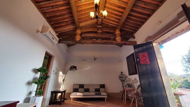 Una habitación acogedora con techo de madera, un sofá, una lámpara y una mesita.