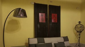 Una habitación con sofá, una mesita, una lámpara de pie y una jaula decorativa.