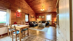 A cozy cabin interior with a dining area, sofa, and fireplace. - Schöne Aussicht by Interhome (Adenau)