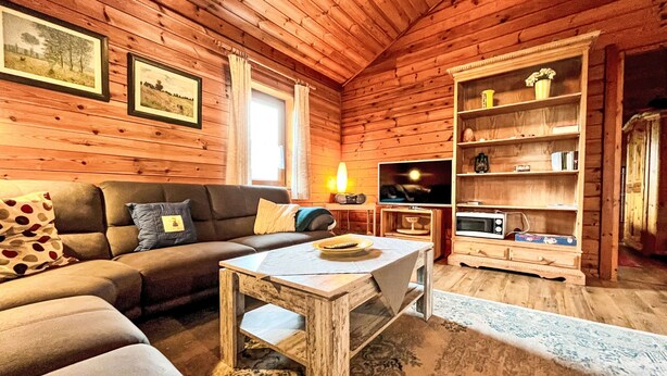 A cozy log cabin interior with a sofa, a coffee table, a television, and a bookshelf. - Schöne Aussicht by Interhome (Adenau)