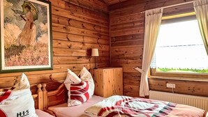 A wooden cabin room with two beds, a painting on the wall, and a window with curtains. - Schöne Aussicht by Interhome (Adenau)
