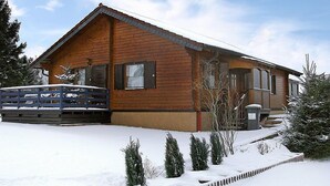 A wooden cabin with a sloped roof, a garage, and a snow-covered yard with small plants. - Schöne Aussicht by Interhome (Adenau)