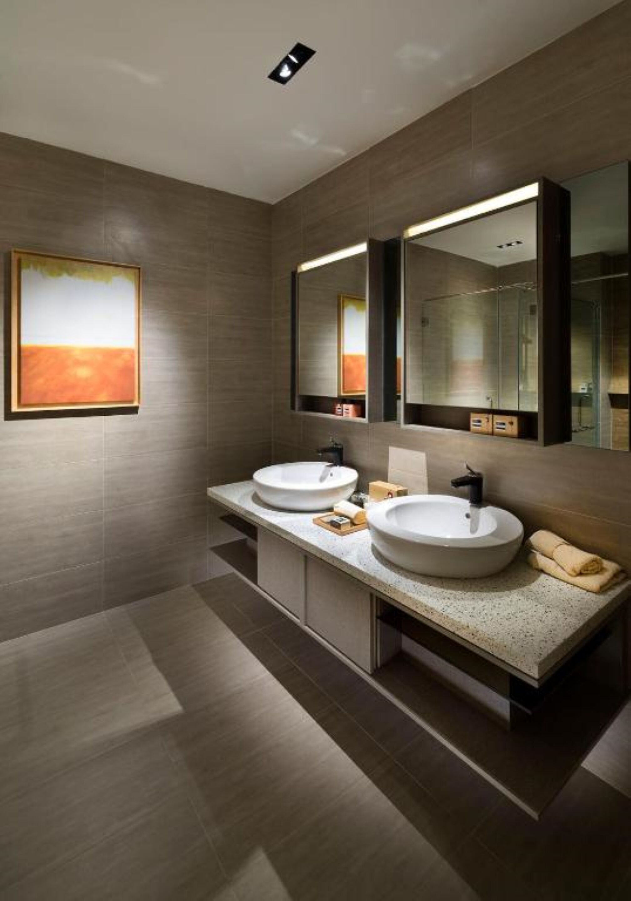 A modern bathroom with two sinks, a large mirror, and a painting on the wall.