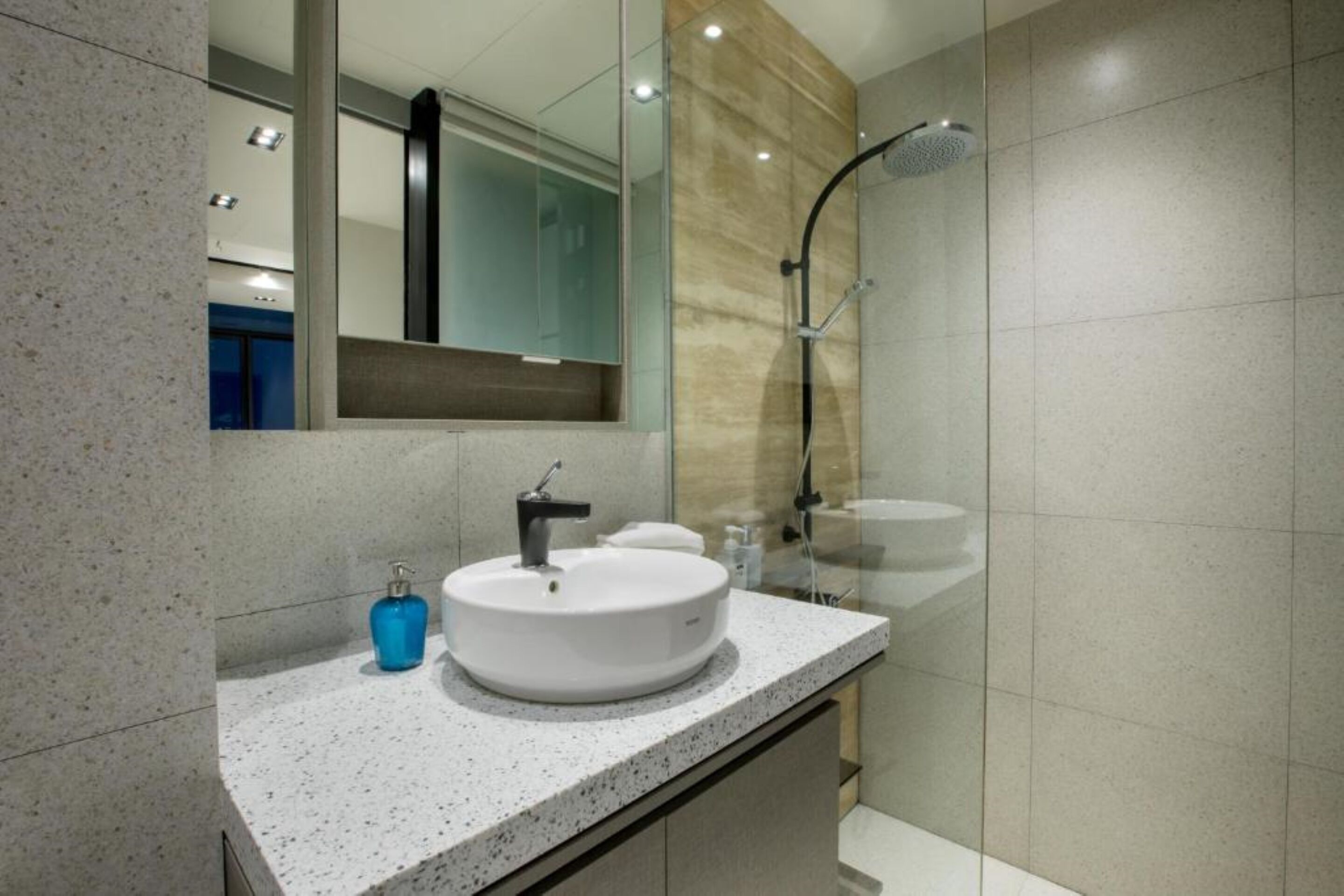 A modern bathroom with a round sink, a mirror, and a shower.