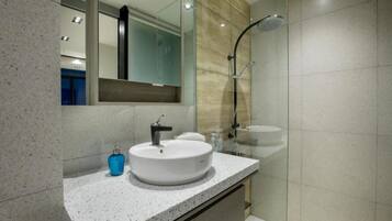 A modern bathroom with a round sink, a mirror, and a shower.