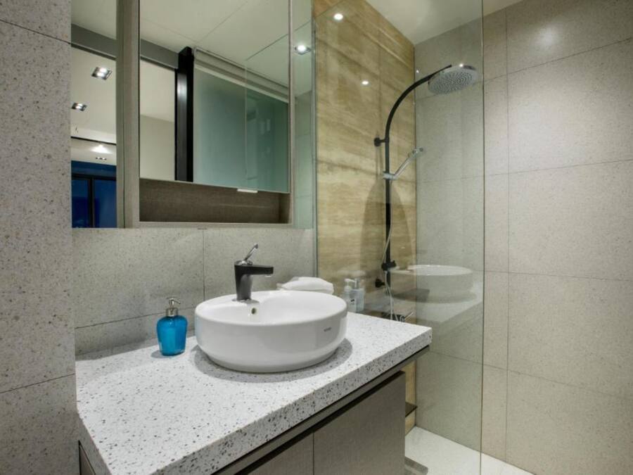 A modern bathroom with a round sink, a mirror, and a shower.