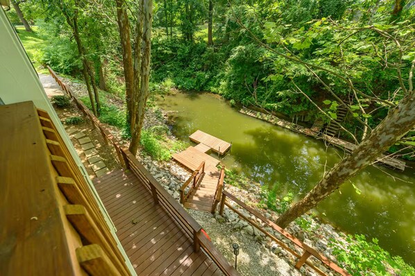 A wooden deck overlooking a river with a wooden bridge and benches.