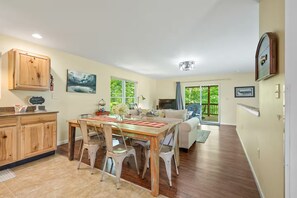 A spacious living area with a dining table, chairs, a sofa, and a television.