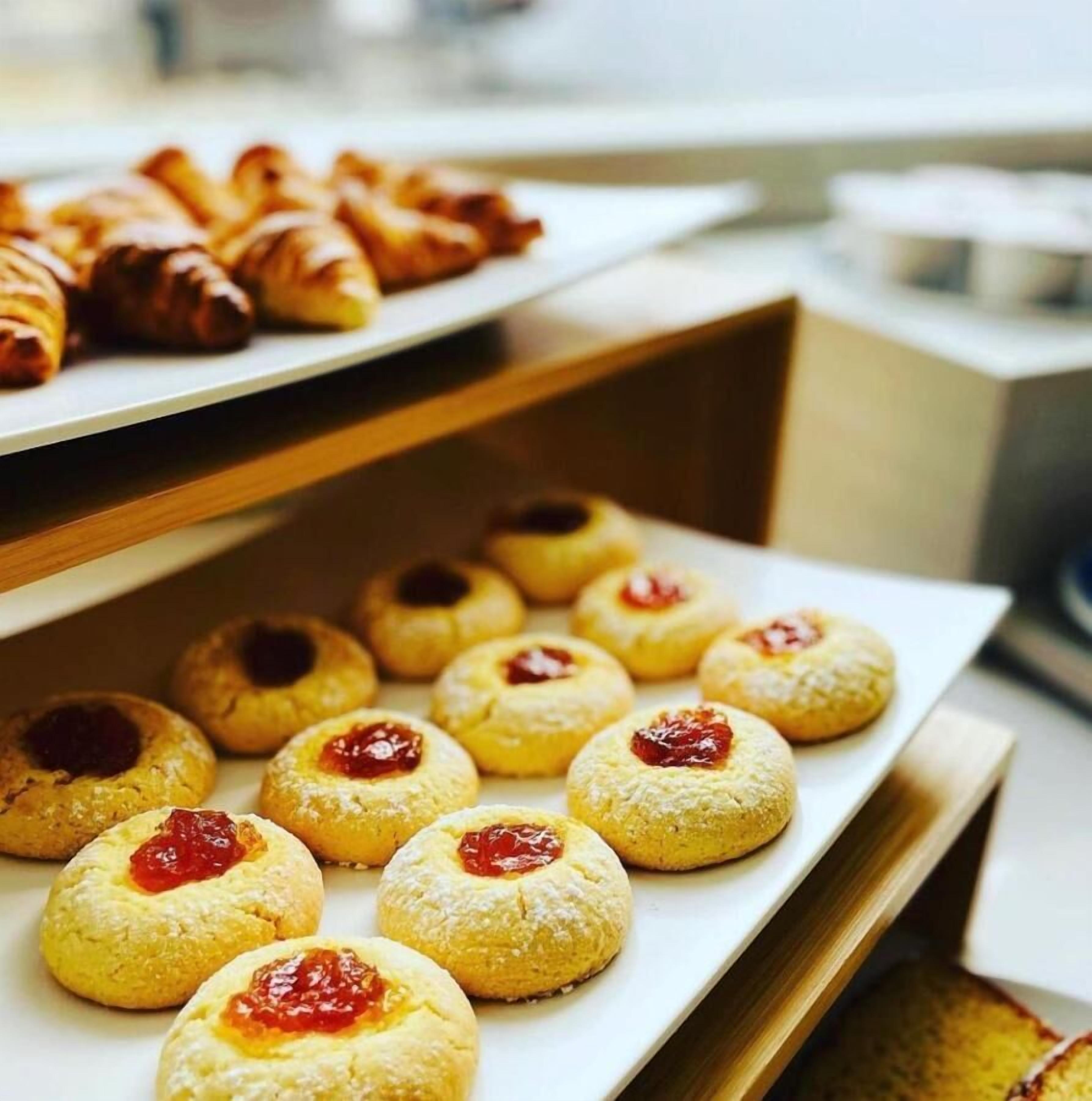 A buffet with various pastries, including scones and cookies with jam.