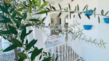 A modern interior with a white railing, potted plants, and a seating area with tables and chairs.