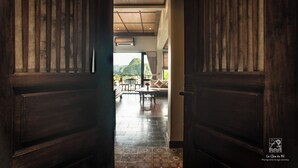 A wooden door leading to a room with a tiled floor, a sofa, and a table. - Le Clos Du Fil (Nam Hoa Lu)