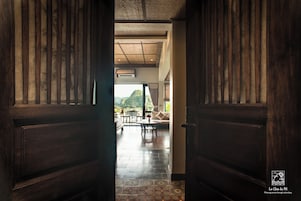 Una puerta de madera que da a una habitación con suelo de baldosas, un sofá y una mesa.