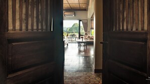 A wooden door leading to a room with a tiled floor, a sofa, and a table. - Le Clos Du Fil (Nam Hoa Lu)