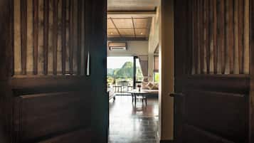 Una puerta de madera que da a una habitación con suelo de baldosas, un sofá y una mesa.